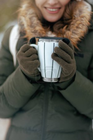 Photo for Closeup on woman outdoors in the city park in winter with mittens and cup of cappuccino - Royalty Free Image