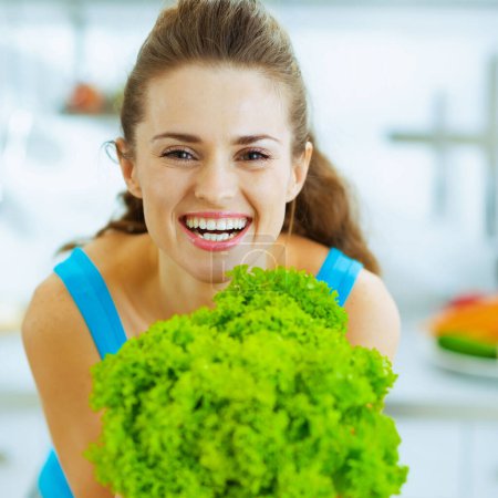 Photo for Happy young woman holding green salad in kitchen - Royalty Free Image