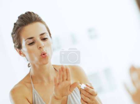 Téléchargez les photos : Jeune femme soufflant sur les ongles après application de vernis à ongles - en image libre de droit