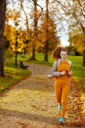 Photo for Hello autumn. fit 40 years old woman in fitness clothes in the park jogging. - Royalty Free Image
