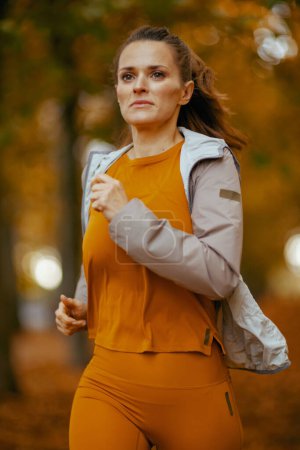 Foto de Hola otoño. joven mujer en ropa de fitness en el parque corriendo. - Imagen libre de derechos