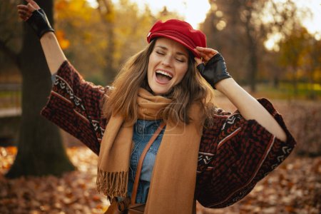 Photo for Hello autumn. smiling trendy woman in red hat with scarf and gloves in the city park. - Royalty Free Image