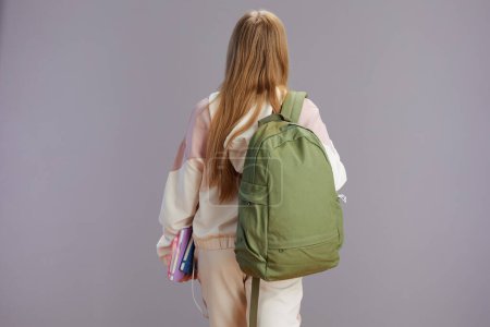 Photo for Seen from behind young woman with backpack and workbooks isolated on grey. - Royalty Free Image
