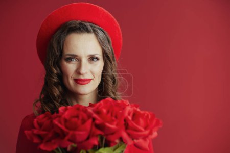 Photo for Happy Valentine. stylish 40 years old woman in red dress and beret on red background with red roses. - Royalty Free Image