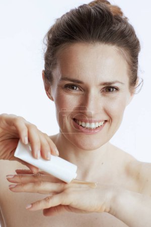 Téléchargez les photos : Femme moderne souriante avec crème pour les mains isolée sur fond blanc. - en image libre de droit