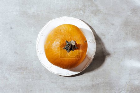 Téléchargez les photos : Plat d'automne posé sur un fond gris avec des citrouilles, feuille d'automne et assiette. - en image libre de droit