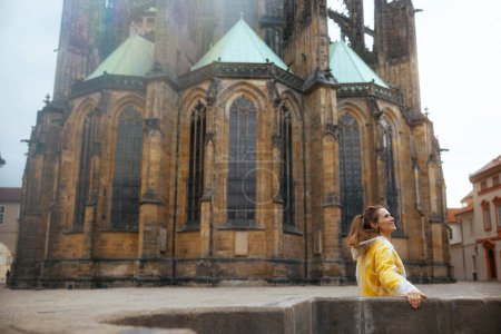 Photo for Smiling stylish woman in yellow blouse and raincoat in Prague Czech Republic having walking tour. - Royalty Free Image