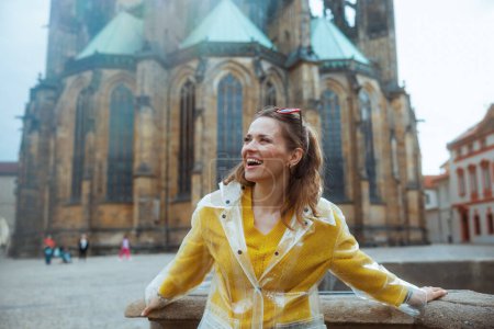 Photo for Smiling modern middle aged traveller woman in yellow blouse and raincoat in Prague Czech Republic having excursion. - Royalty Free Image