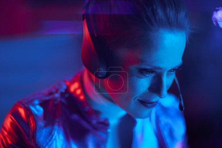 Foto de Concepto futurista neón metaverso. mujer de negocios elegante con auriculares que tienen chat de vídeo en la oficina moderna. - Imagen libre de derechos