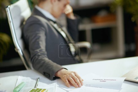 Photo for New job. Closeup on modern woman worker in modern green office in grey business suit with employee termination letter. - Royalty Free Image