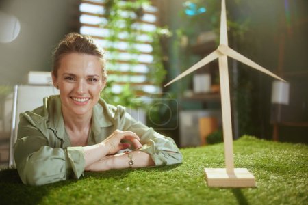 Téléchargez les photos : Eco Business. heureuse élégante propriétaire de petite entreprise femme en chemisier vert dans le bureau vert moderne avec moulin à vent - en image libre de droit