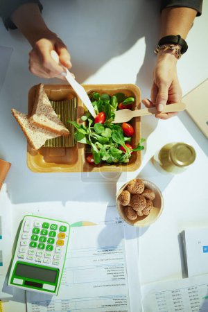 Photo for Sustainable workplace. Upper view of business woman in green office eating salad. - Royalty Free Image
