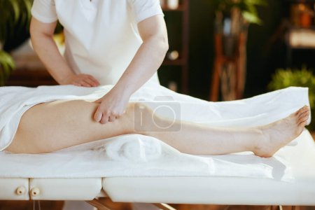 Téléchargez les photos : Temps de santé. Gros plan sur massothérapeute dans le salon de spa masser les clients jambe sur table de massage. - en image libre de droit