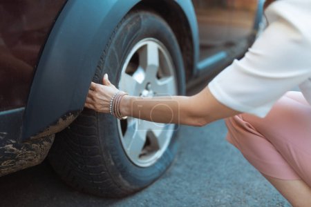 Photo for Car accident. Closeup on tourist woman in the city touching flat tire. - Royalty Free Image
