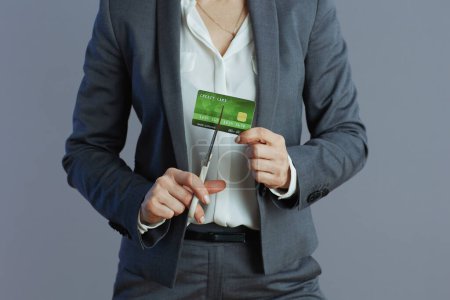 Photo for Closeup on female employee in grey suit with credit card and scissors isolated on gray. - Royalty Free Image