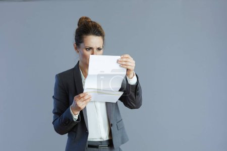 Téléchargez les photos : Jeune femme d'affaires en costume gris avec document sur fond gris. - en image libre de droit