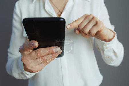 Photo for Closeup on small business owner woman in white blouse driving the growth of social media using smartphone isolated on gray background. - Royalty Free Image