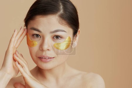 Photo for Portrait of modern asian woman with eye patches isolated on beige background. - Royalty Free Image