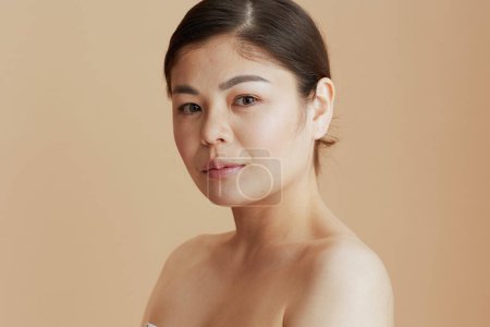 Téléchargez les photos : Portrait de jeune asiatique femelle regardant à la caméra sur fond beige. - en image libre de droit