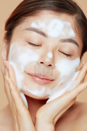 Téléchargez les photos : Relaxé moderne asiatique femme lavage visage. - en image libre de droit