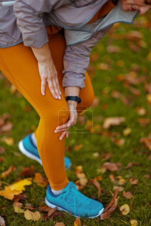 Photo for Hello autumn. Closeup on middle aged woman in fitness clothes in the park having leg pain. - Royalty Free Image