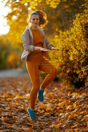 Photo for Hello autumn. Full length portrait of modern female in fitness clothes in the park workout. - Royalty Free Image