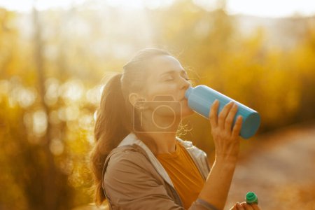 Photo for Hello autumn. elegant woman in fitness clothes in the park with bottle of water. - Royalty Free Image
