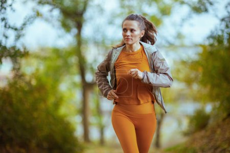 Photo for Hello autumn. fit woman in fitness clothes in the park running. - Royalty Free Image