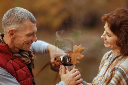 Foto de Hola otoño. sonriente familia con estilo en el parque con hoja de otoño, taza de café y termos. - Imagen libre de derechos