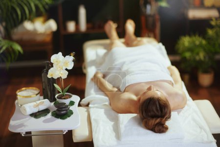Téléchargez les photos : Temps de santé. moderne détendue femme d'âge moyen dans le salon de spa pose sur la table de massage. - en image libre de droit
