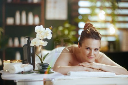 Téléchargez les photos : Temps de santé. femme moderne détendue dans une armoire de massage posée sur une table de massage. - en image libre de droit