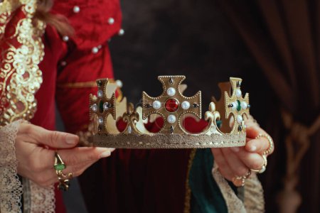 Photo for Closeup on medieval queen in red dress with crown on dark gray background. - Royalty Free Image
