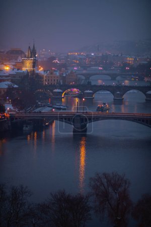 Foto de Paisaje en invierno en Praga, República Checa con el río Moldava, barco y puente por la noche. - Imagen libre de derechos