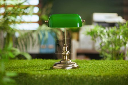 Téléchargez les photos : Il est temps de passer à l'éco. table d'herbe dans le bureau vert moderne avec lampe. - en image libre de droit