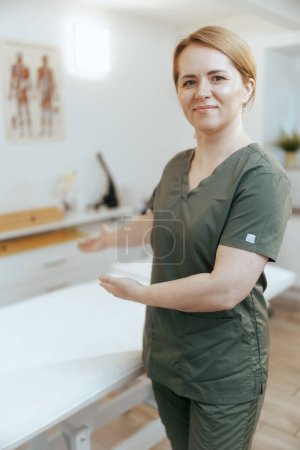 Photo for Healthcare time. happy female medical massage therapist in massage cabinet welcoming. - Royalty Free Image