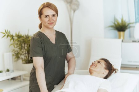 Téléchargez les photos : Temps de santé. souriant massothérapeute féminine dans l'armoire de massage avec le client conduisant l'examen. - en image libre de droit