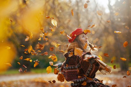 Téléchargez les photos : Bonjour l'automne. heureuse femme élégante en chapeau rouge avec écharpe se réjouissant dans le parc de la ville. - en image libre de droit
