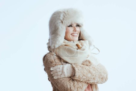 Photo for Happy modern middle age woman in winter coat and fur hat isolated on white background in white gloves hugging herself. - Royalty Free Image