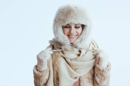 Foto de Sonriente elegante mujer de 40 años en abrigo de invierno y sombrero de piel aislado sobre fondo blanco en guantes blancos. - Imagen libre de derechos