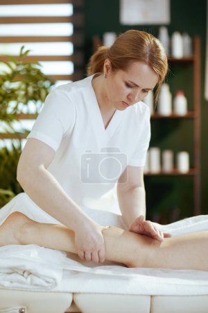 Téléchargez les photos : Temps de santé. massothérapeute médical dans l'armoire de massage massant les clients jambe sur table de massage. - en image libre de droit