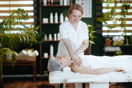 Photo for Healthcare time. massage therapist in spa salon massaging clients shoulder on massage table. - Royalty Free Image