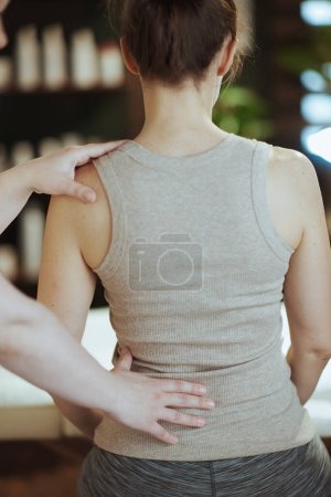 Photo for Healthcare time. Seen from behind massage therapist in spa salon checking clients back condition during checkup. - Royalty Free Image