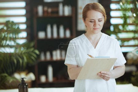 Photo for Healthcare time. massage therapist woman in massage cabinet with clipboard. - Royalty Free Image