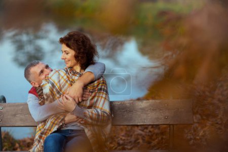 Téléchargez les photos : Bonjour l'automne. petit ami élégant souriant et petite amie dans le parc embrassant tout en étant assis sur le banc. - en image libre de droit