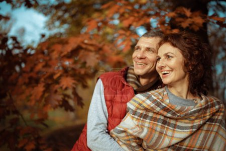 Téléchargez les photos : Bonjour l'automne. couple romantique souriant dans le parc regardant au loin. - en image libre de droit