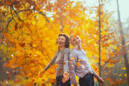 Foto de Hola otoño. alegre elegante novio y novia en el parque lanzando hojas de otoño. - Imagen libre de derechos