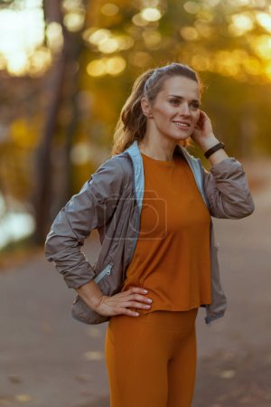 Foto de Hola otoño. mujer sonriente en forma en ropa de fitness en el parque relajante después del entrenamiento. - Imagen libre de derechos