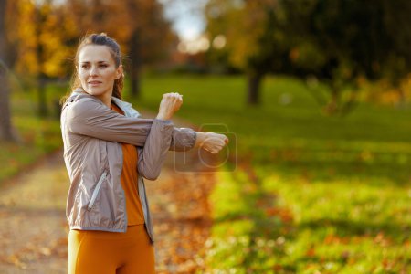Foto de Hola otoño. mujer con estilo en ropa de fitness en el parque de estiramiento. - Imagen libre de derechos