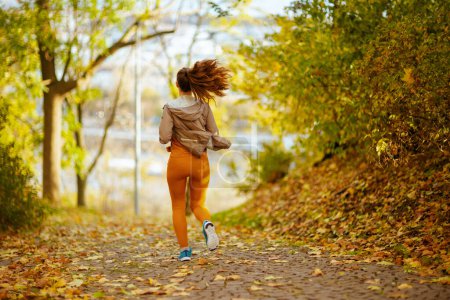 Photo for Hello autumn. Seen from behind woman in fitness clothes in the park running. - Royalty Free Image