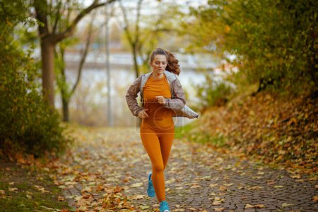 Photo for Hello autumn. Full length portrait of elegant woman in fitness clothes in the park running. - Royalty Free Image